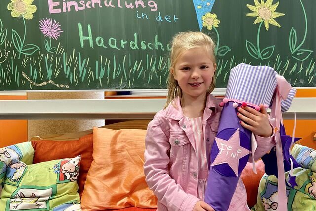 Die Erstklässlerin Josefine sitzt in Oer-Erkenschwick mit ihrer Schultüte auf einer Bank in der Haardschule.