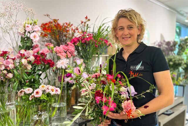 Carolin Beforth steht vor einem Regal mit vielen bunten Schnittblumen.