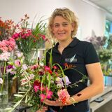 Carolin Beforth steht vor einem Regal mit vielen bunten Schnittblumen.