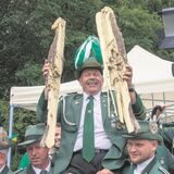 Ein neuer Schützenkönig wird von seinen Kameraden auf den Schultern getragen, in den Händen hält er die Überreste des Schützenvogels. Davor ein Mann mit einer Videokamera.