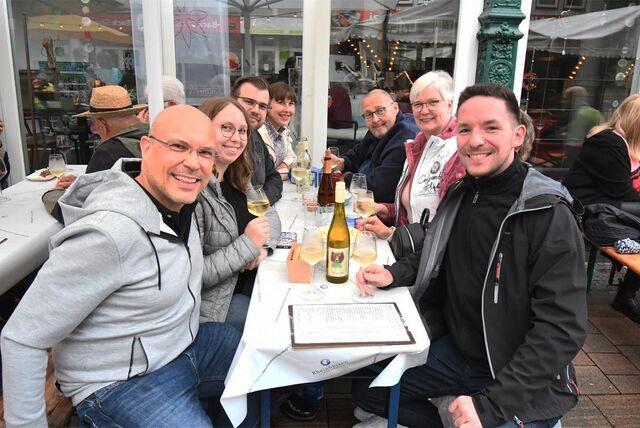 Mehrere Menschen sitzen gemeinsam und trinken Wein.
