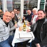 Mehrere Menschen sitzen gemeinsam und trinken Wein.