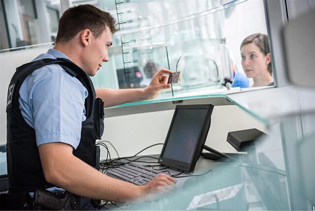 Ein Bundespolizist kontrolliert den Personalausweis einer Reisenden (Symbolfoto).