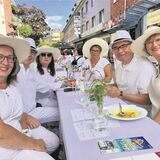 Sechs Personen mit weißen Hüten an der White-Dinner-Tafel.