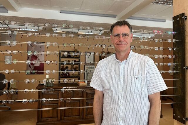 Peter Schanz vor ganz vielen Brillen in seinem Optiker-Geschäft.