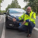 Ralf Feldhaus vom Dattelner Ordnungsamt hockt vor einem schwarzen Kia Ceed. Er hält den rechten Daumen nach oben.