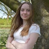 Luise Storm lehnt sich an einem Baum an. Im Hintergrund sind Grünflächen zu sehen.