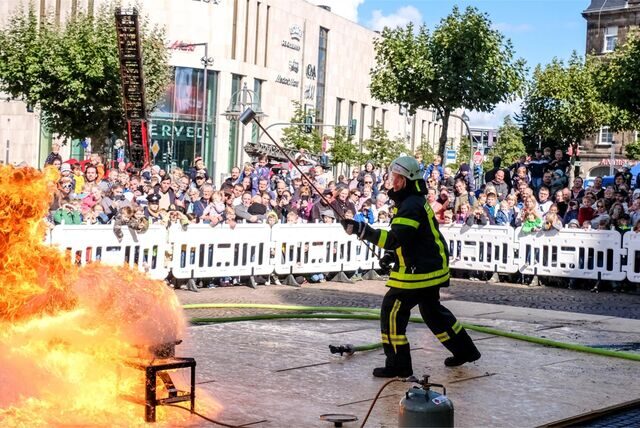 Ein Feuerwehrmann der Recklinghäuser Feuerwehr löscht zu Demonstrationszwecken einen Brand auf dem Rathausplatz.