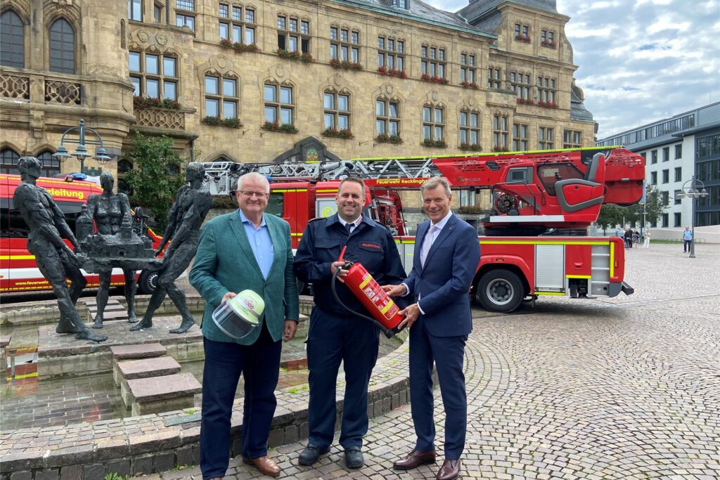 Bürgermeister Christoph Tesche, der Leiter der Feuerwehr Thorsten Schild und der Erste Beigeordnete Ekkehard Grunwald stehen vor einem Feuerwehrwagen vor dem Rathaus Recklinghausen.