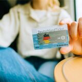 Das DeutschlandTicket wird in die Kamera gehalten.