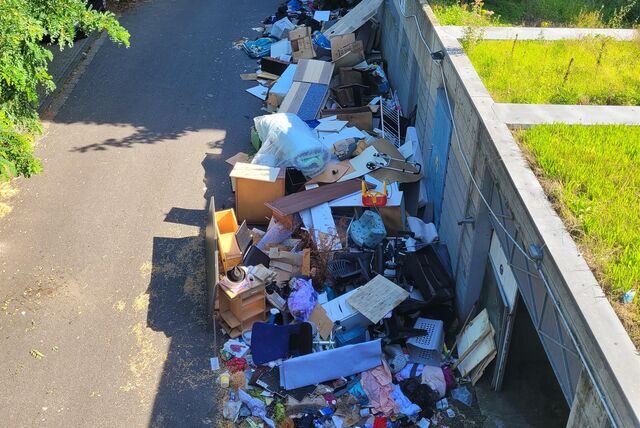 Abfall und Sperrmüll türmen sich vor einer Gebäudewand.