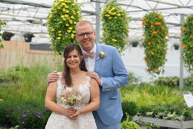 Christin und Sebastian Schulz stehen in der Gärtnerei. Im Hintergrund sind viele Pflanzen zu sehen.