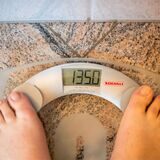 Füße auf einer Waage, die ein Gewicht von 135 Kilo anzeigt.