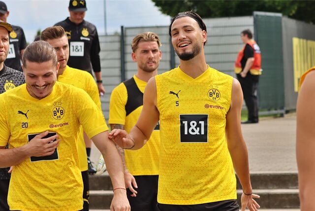 Ramy Bensebaini und Marcel Sabitzer gehen lachend Richtung Trainingsplatz.