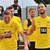 Ramy Bensebaini und Marcel Sabitzer gehen lachend Richtung Trainingsplatz.