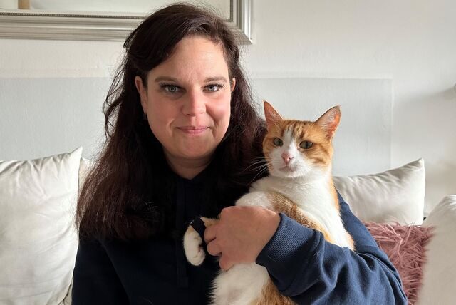 Tina Uhländer sitzt auf der Couch mit einer Katze im Arm.