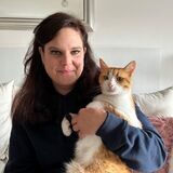 Tina Uhländer sitzt auf der Couch mit einer Katze im Arm.