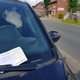 Ein Knöllchen, das hinter dem Scheibenwischer eines Autos angebracht wurde. (Symbolbild)