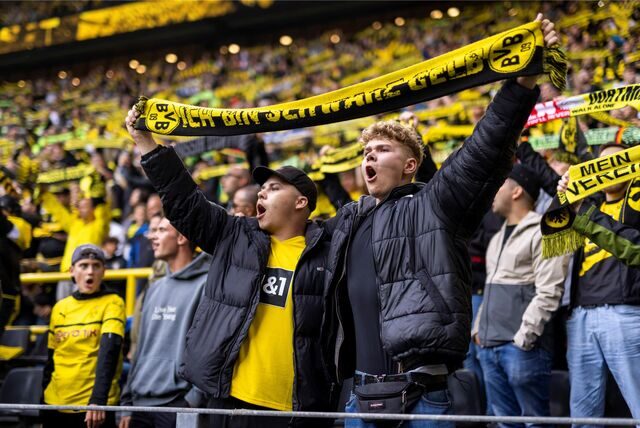 Zwei BVB-Fans halten einen Schal in die Luft.