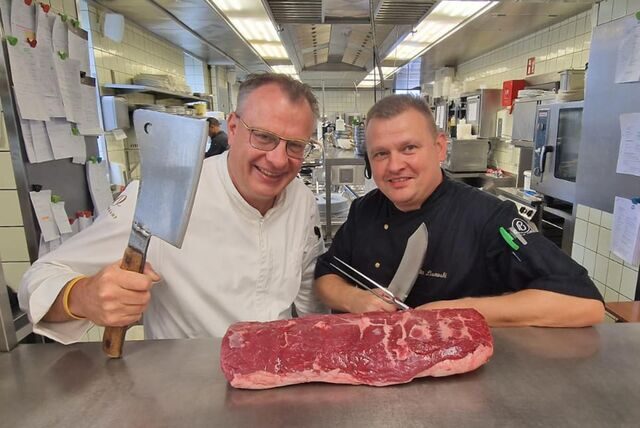 Koch Günther Overkamp steht mit einem Mitarbeiter in seiner Küche in Dortmund, vor ihnen liegt ein Stück Rindfleisch.