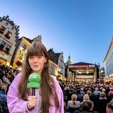 RZ-Redakteurin Janka Hardenacke mit Mikrofon, im Hintergrund der Altstadtmark in Recklinghausen mit Publikum und Bühne