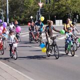 Kinder und Erwachsene bei Fahrraddemo „Kidical Mass“ mit Ballons auf der Straße