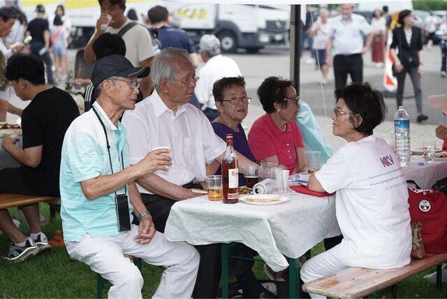 Männer und Frauen koreanischer Herkunft sitzen am Tisch unter einem Pavillon auf dem Europaplatz in Castrop-Rauxel.
