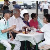Männer und Frauen koreanischer Herkunft sitzen am Tisch unter einem Pavillon auf dem Europaplatz in Castrop-Rauxel.