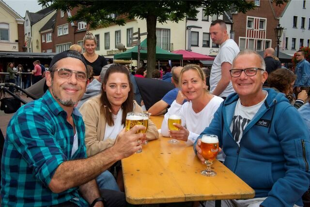 Vier Menschen sitzen an einem Biertisch und prosten in die Kamera.