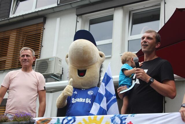 Ex-Fußballer Ingo Anderbrügge steht neben Maskottchen Erwin und einem Organisator vor dem „Haus Regenbogen“ in Recklinghausen.
