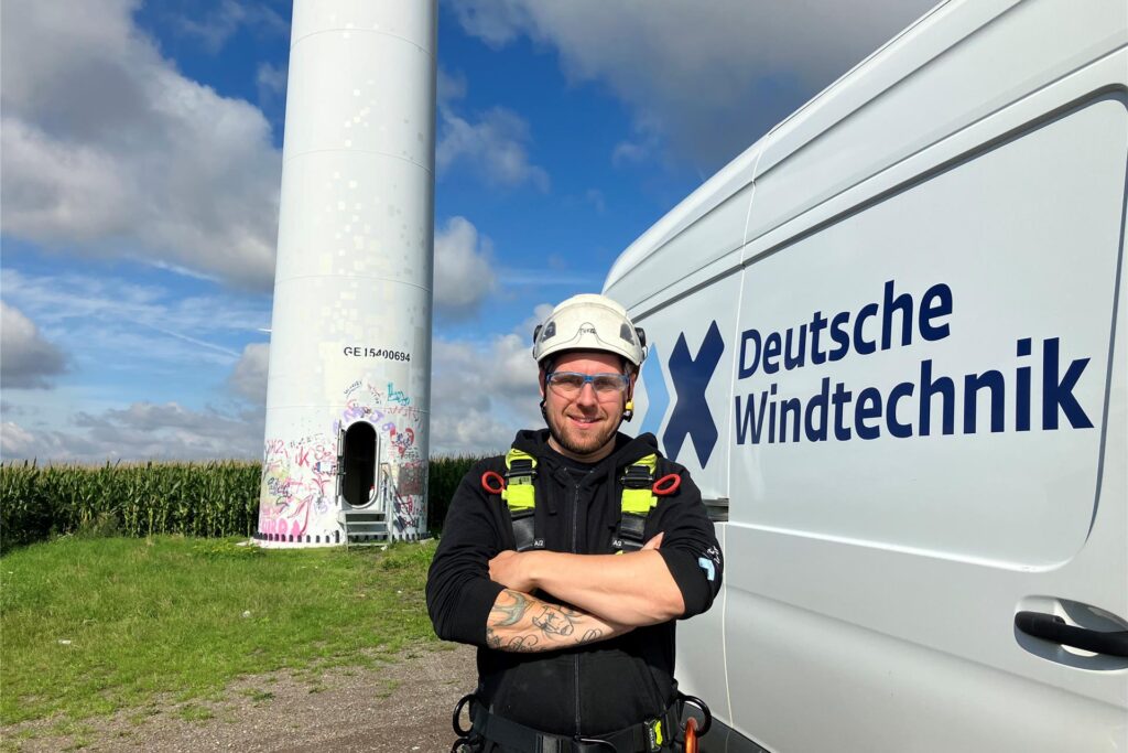 Marco Thiel (33) in Ausrüstung vor einem Windrad im Windpark Hamm