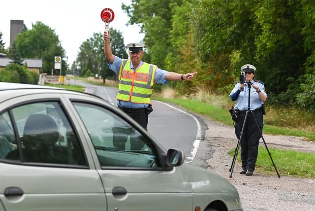 Ein Polizist mit einer Warnkelle winkt ein Fahrzeug aus dem Verkehr.