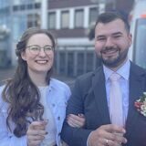 Paula und Fabian stehen nach ihrer Trauung auf dem Friedensplatz in Dortmund. Im Hintergrund ist ein Rettungswagen zu sehen.