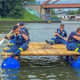 Vier Mitglieder des THW paddeln auf einem selbstgebastelten Floß.  (Vorne, von links: Truppführer Merlin Dwinger und Timo Schmidt. Hinten, von links: Gruppenführer Alexander Hülsdau und Pascal Binz)