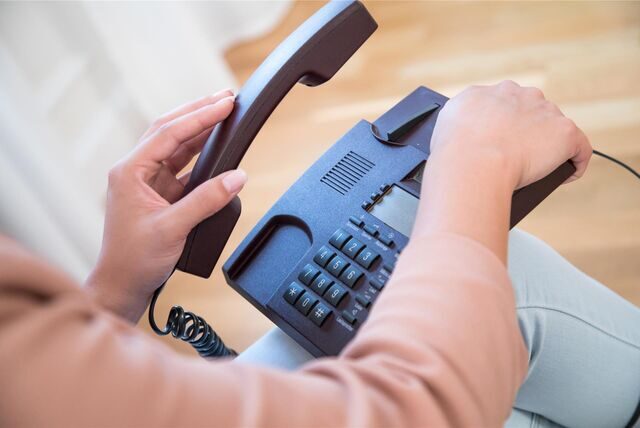 Mensch nimmt Telefonhörer ab.