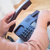 Mensch nimmt Telefonhörer ab.