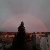Ein rötlicher Bogen ist am Himmel zu sehen. Im Vordergrund eine Wohnsiedlung.
