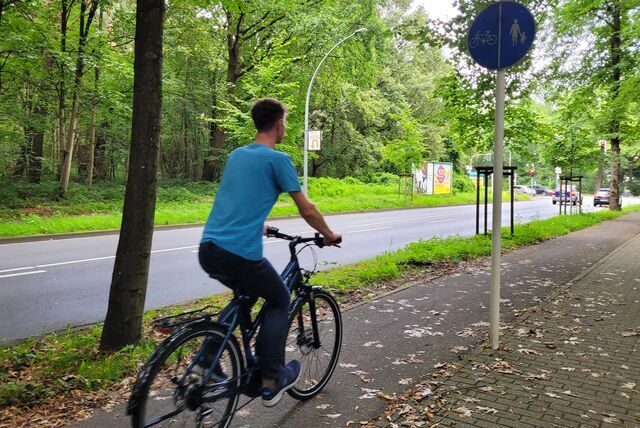 Ein Mann fährt Fahrrad auf einem Radweg.