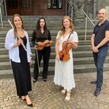 Die NPW-Musikerinnen Teresa Cabezas Campoy, Mariana Hernández Gonzáles und Mariya Manasieva (v.l.) und GMD Rasmus Baumann stehen vorm Rathaus in Recklinghausen.