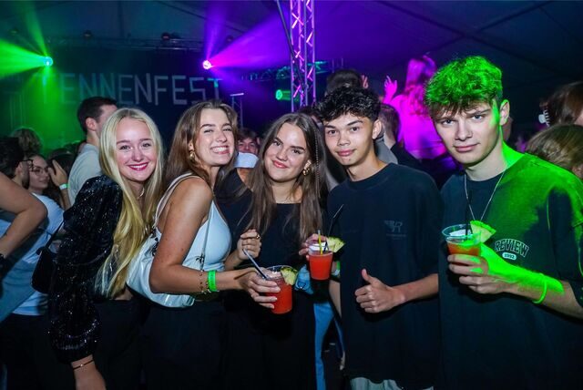 Fünf junge Menschen strahlen mit Drinks in der Hand in die Kamera.