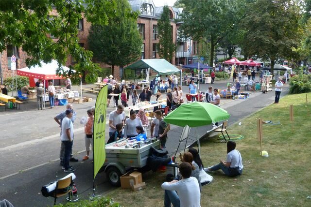 Eindrücke vom Stadtteilfest „Nord feiert“ aus dem Jahr 2016, bunte Stände stehen am Straßenrand und Besucher schauen sich das Angebot an