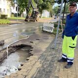 Zwei Männer in Arbeitskleidung stehen neben einem Loch in der Straße am Westring.