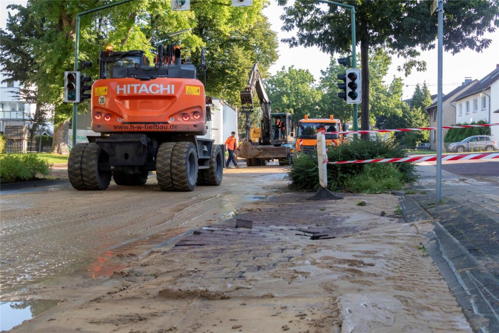 Baufahrzeuge stehen auf einer Straße in Datteln, im Vordergrund unterspültes Pflaster. Baufahrzeuge stehen auf einer Straße in Datteln, im Vordergrund unterspültes Pflaster.