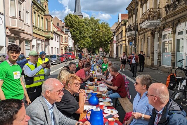 Bierbänke und -tische stehen auf der Marienstraße in Recklinghausen. Menschen sitzen daran, essen und trinken und reden miteinander.