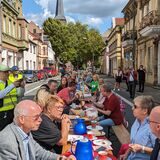 Bierbänke und -tische stehen auf der Marienstraße in Recklinghausen. Menschen sitzen daran, essen und trinken und reden miteinander.