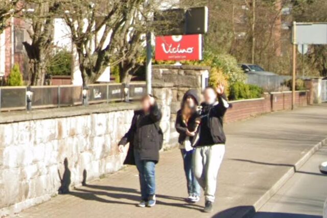 Eine Gruppe von Jugendlichen winkt und streckt den Mittelfinger in die Kamera des Google Street View Fahrzeuges.