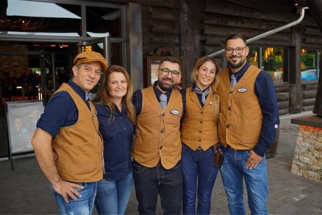 Fünf Menschen stehen auf einer Terrasse vor einem Restaurant.