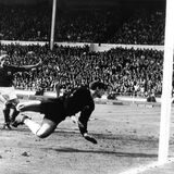 Der vom englischen Stürmer Geoff Hurst (nicht im Bild) geschossene Ball knallt von der Latte auf den Boden. Der deutsche Torhüter Hans Tilkowski (vorn) schaut sich im Hechten um, Abwehrspieler Wolfgang Weber (l) und der jubelnde englische Stürmer Roger Hunt schauen zu. Das sogenannte Wembley-Tor machte Hans Tilkowski berühmt.