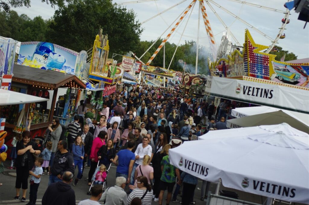 Besucher gehen zwischen den Fahrgeschäften und Ständen auf der Hüstener Kirmes entlang. Besucher gehen zwischen den Fahrgeschäften und Ständen auf der Hüstener Kirmes entlang.
