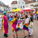 Menschen tanzen beim CSD auf dem Marktplatz. Einige sind in Regenbogenfahnen gehüllt.